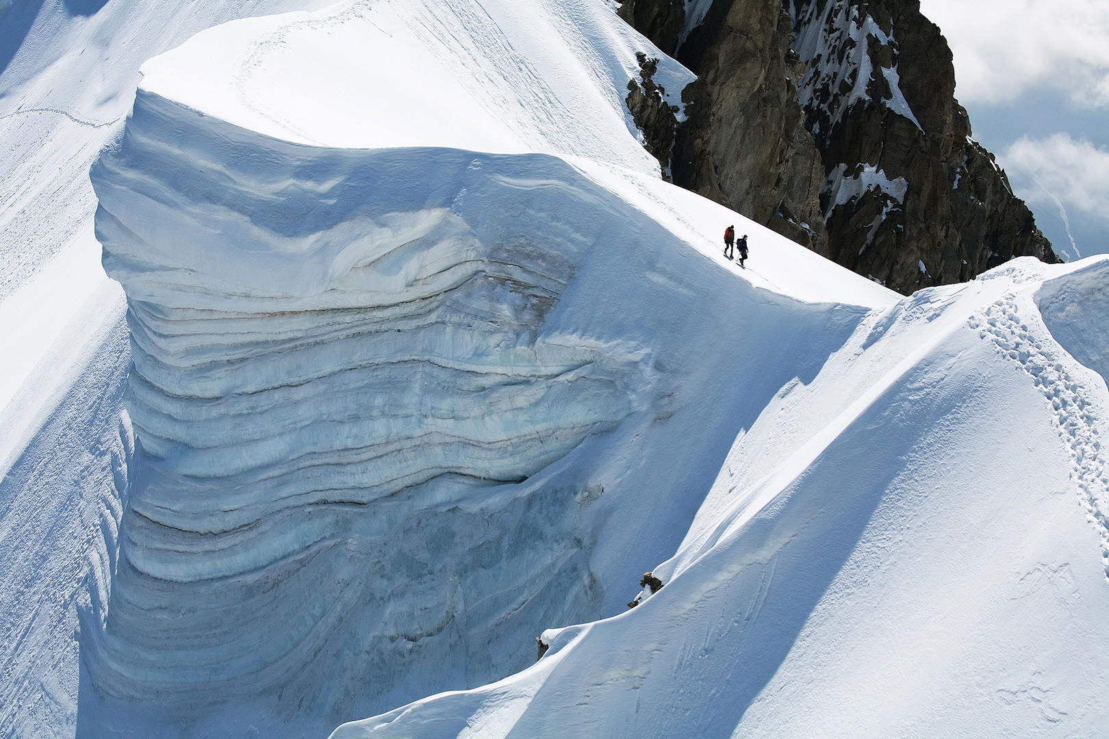Two alpinists on the Rochefort Ridge traverse, France — moving light and fast, the pack volume a commitment rather than a compromise