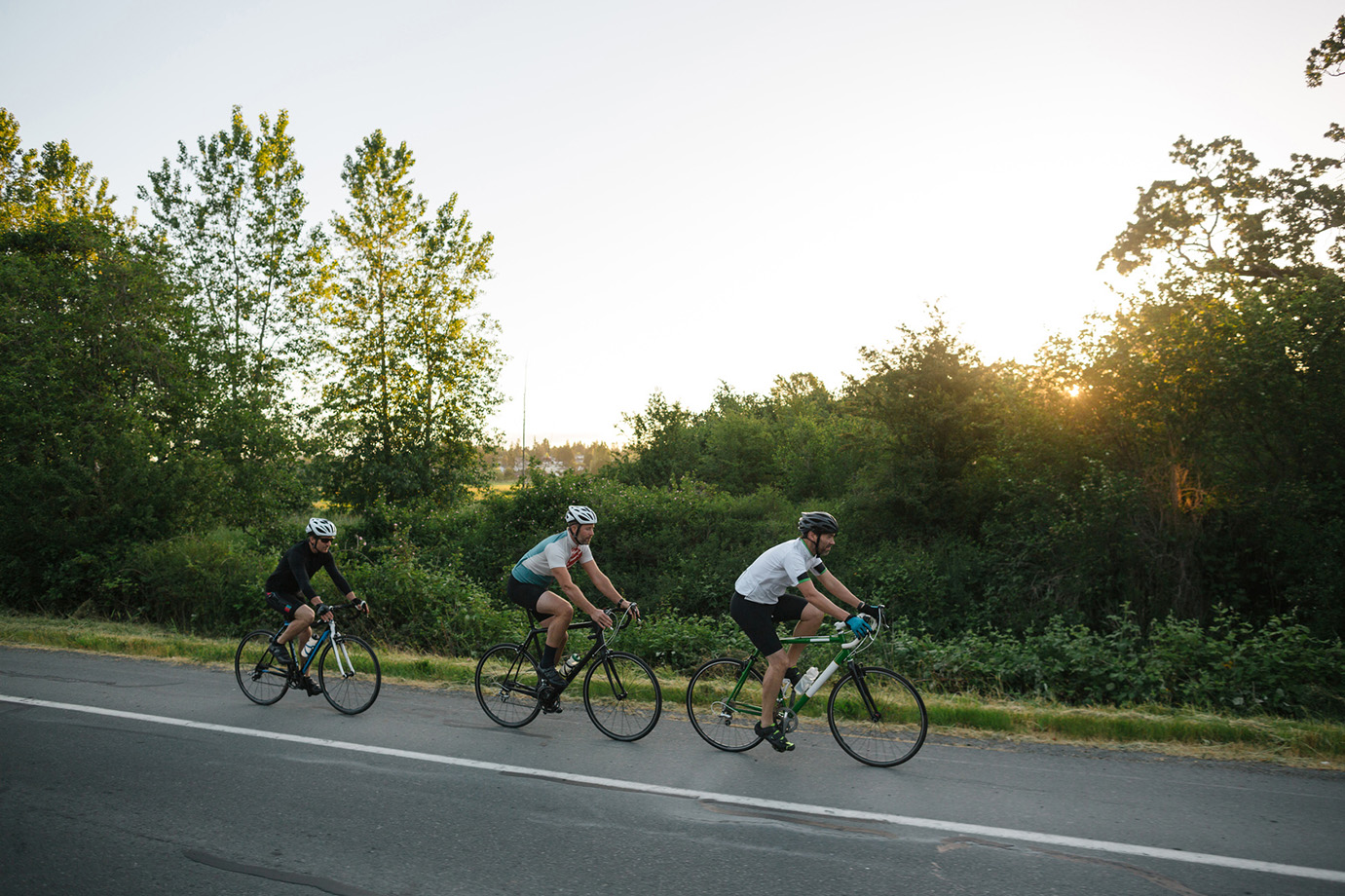 Road cyclists riding hard on a rolling descent — the approach roads between the great cols carry this same sense of controlled momentum
