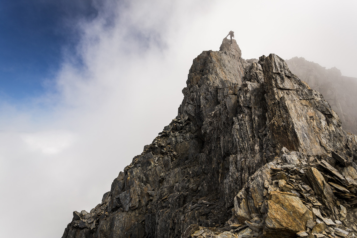 Low angle view of a climber working a steep mountain face — the exposure that Yosemite granite eventually demands of anyone who wants to move past the moderate grades