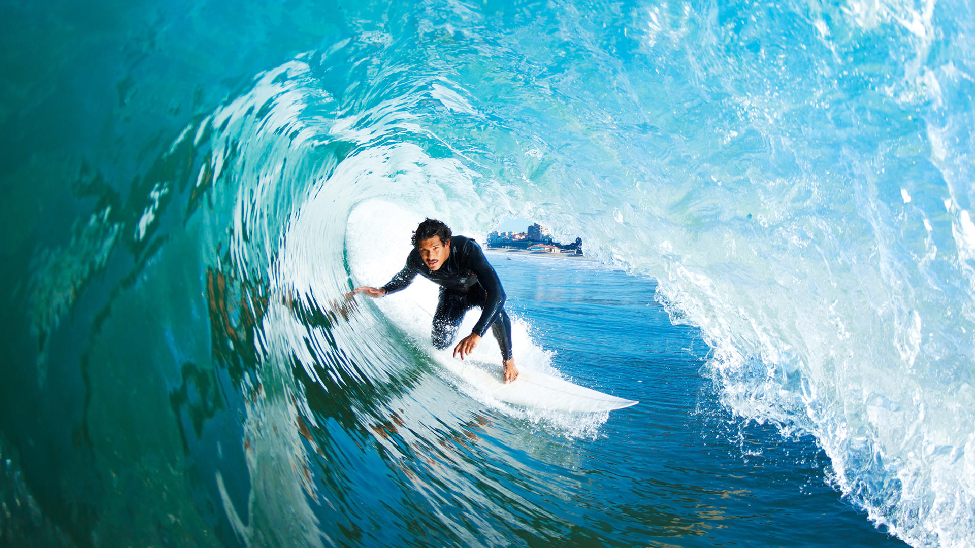 Dropping into a wave at a rocky coastal surf spot — the same commitment the Lofoten breaks demand, with considerably less neoprene required
